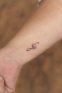Tatuaje en línea fina de una clave de sol