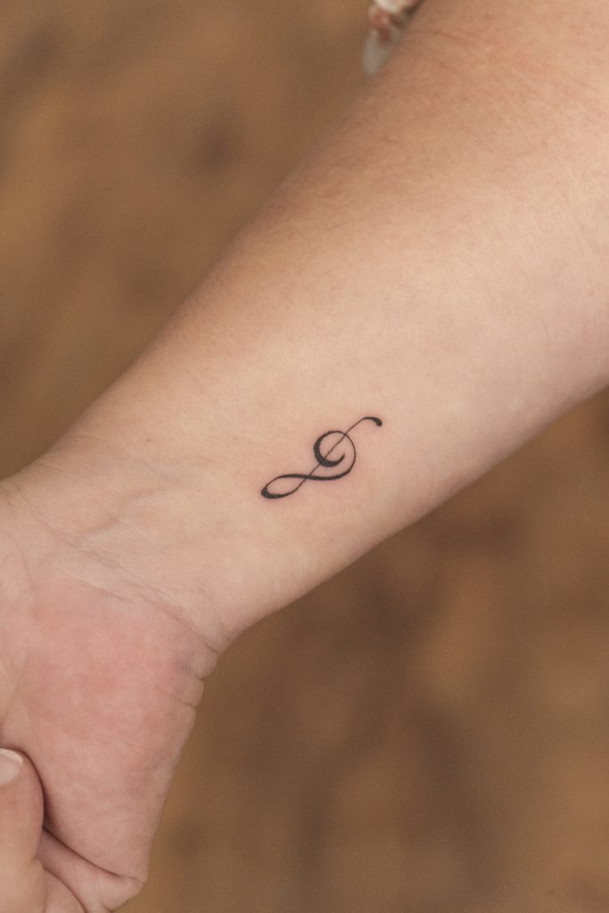 Tatuaje en línea fina de una clave de sol